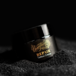 Unmistakable - Vegane Premium Tattoopflege - Repair Tattoo Cream Glas auf schwarzem Sand