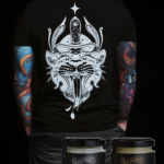 Unmistakable Dagger Thrust Box - Junger Mann mit schwarzem T-Shirt von hinten fotografiert und REPAIR Tattoo Creme und CARE Moisture Balm